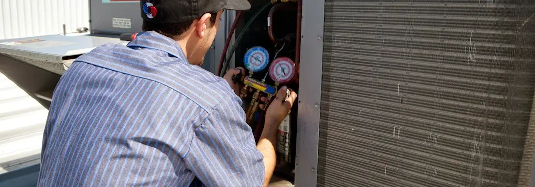 HVAC technician servicing a condenser unit in Hilton